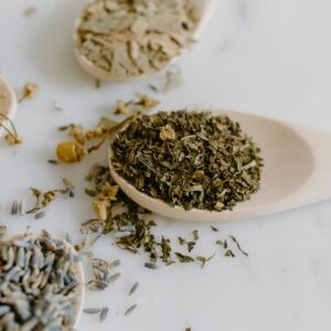 A collection of dried herbs on wooden spoons for natural remedies and alternative medicine.